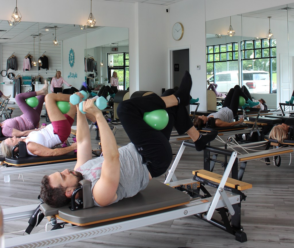 Pilates students using medicine balls and weights